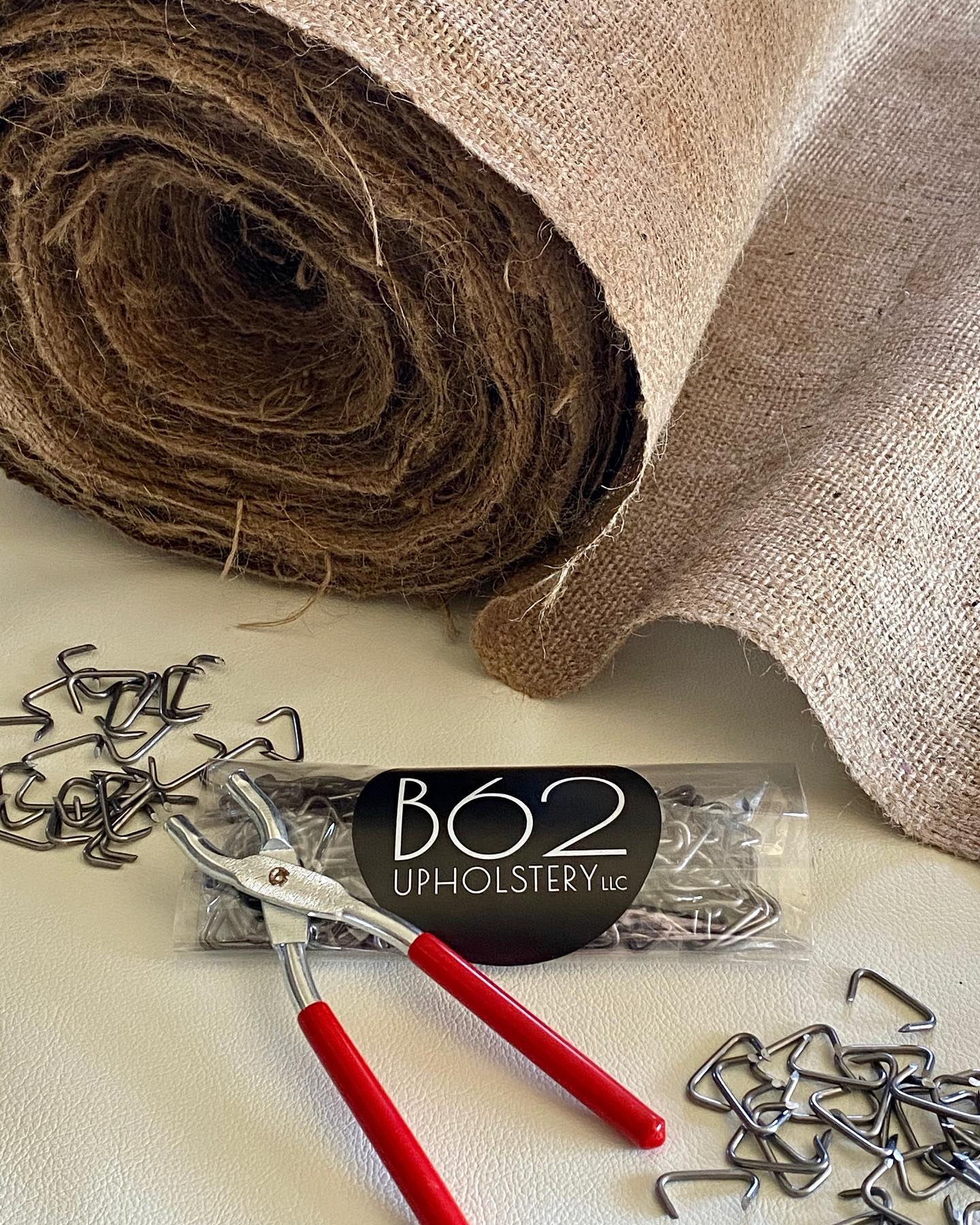 B62 upholstery tools, hog rings, and burlap roll for seat installation.